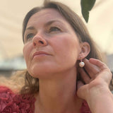 Woman adjusting a pearl earring with a blurred background