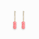 Pair of pink beaded earrings on a white background, photographed from the