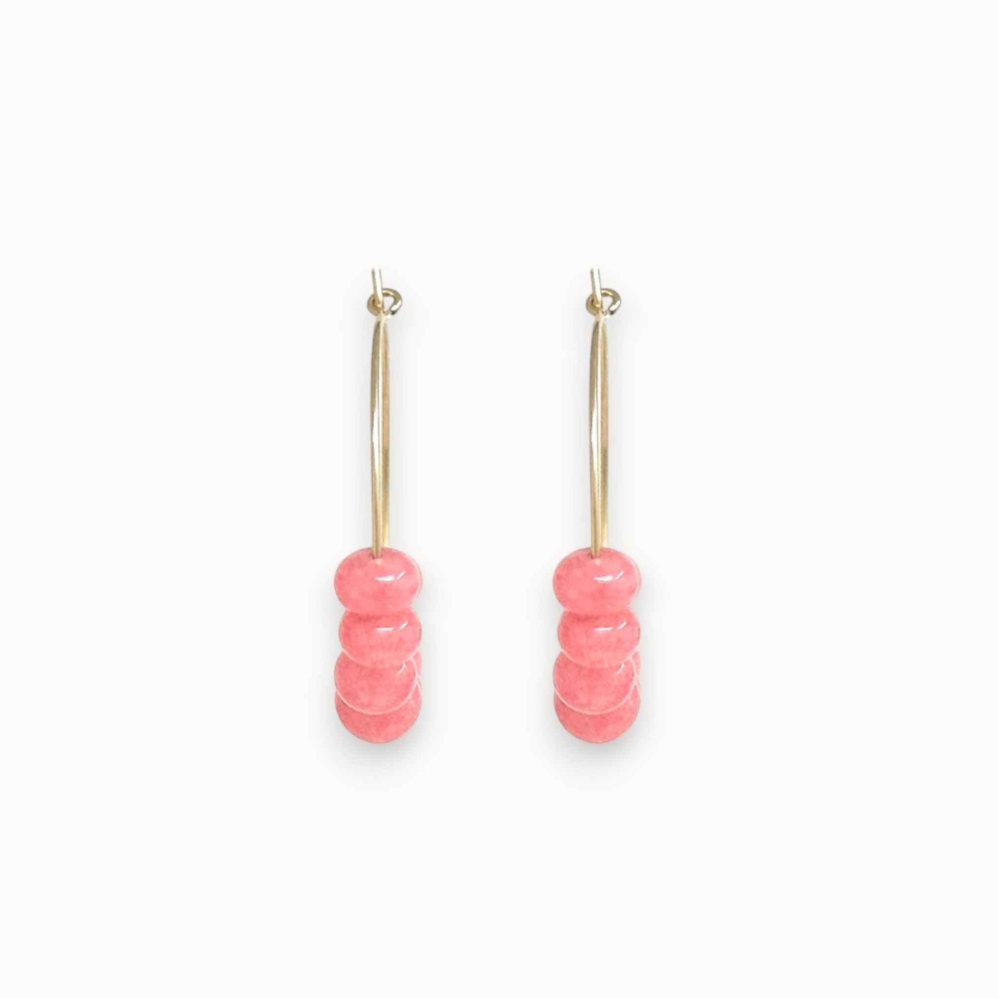 Pair of pink beaded earrings on a white background, photographed from the