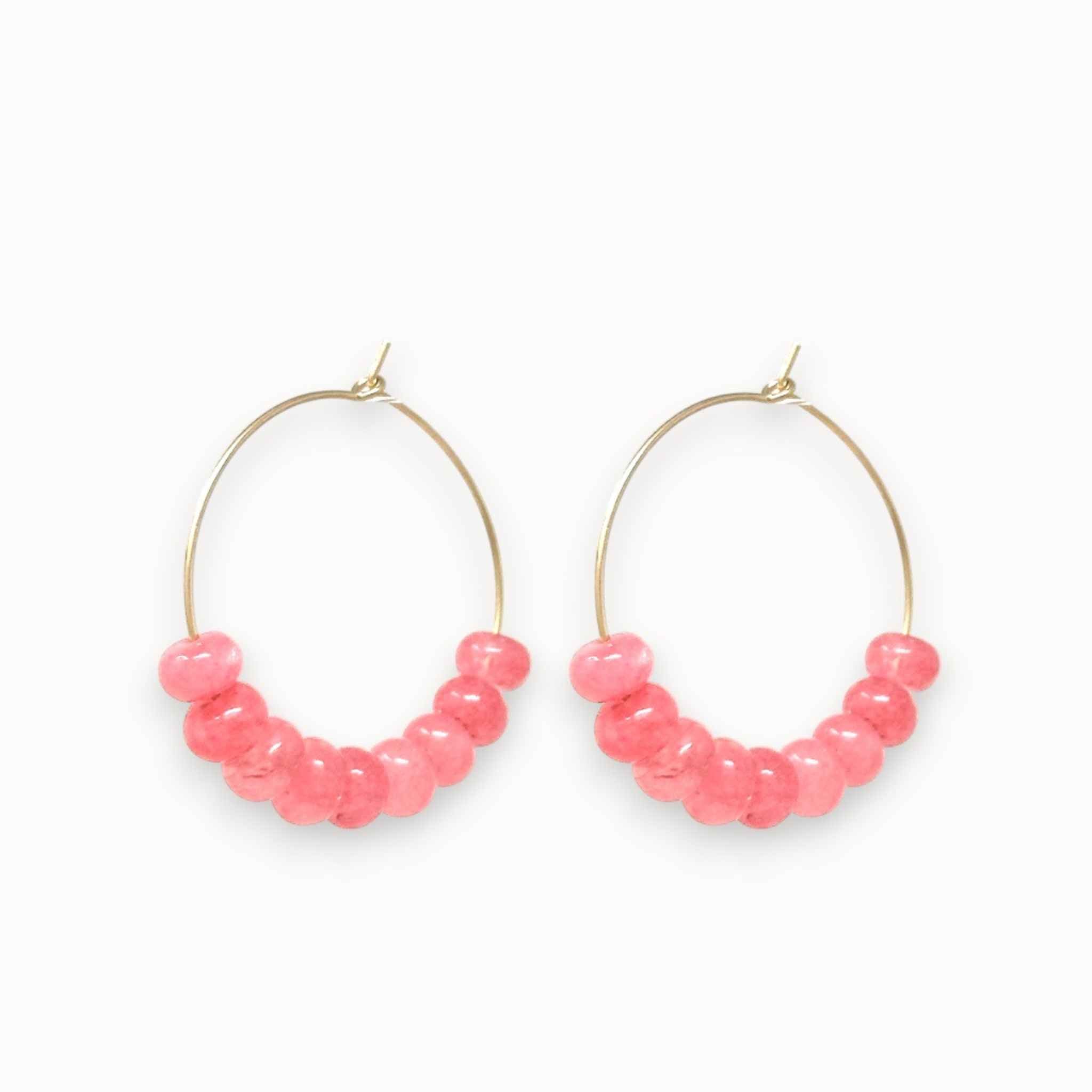Gold hoop earrings with pink jade beads on a white background