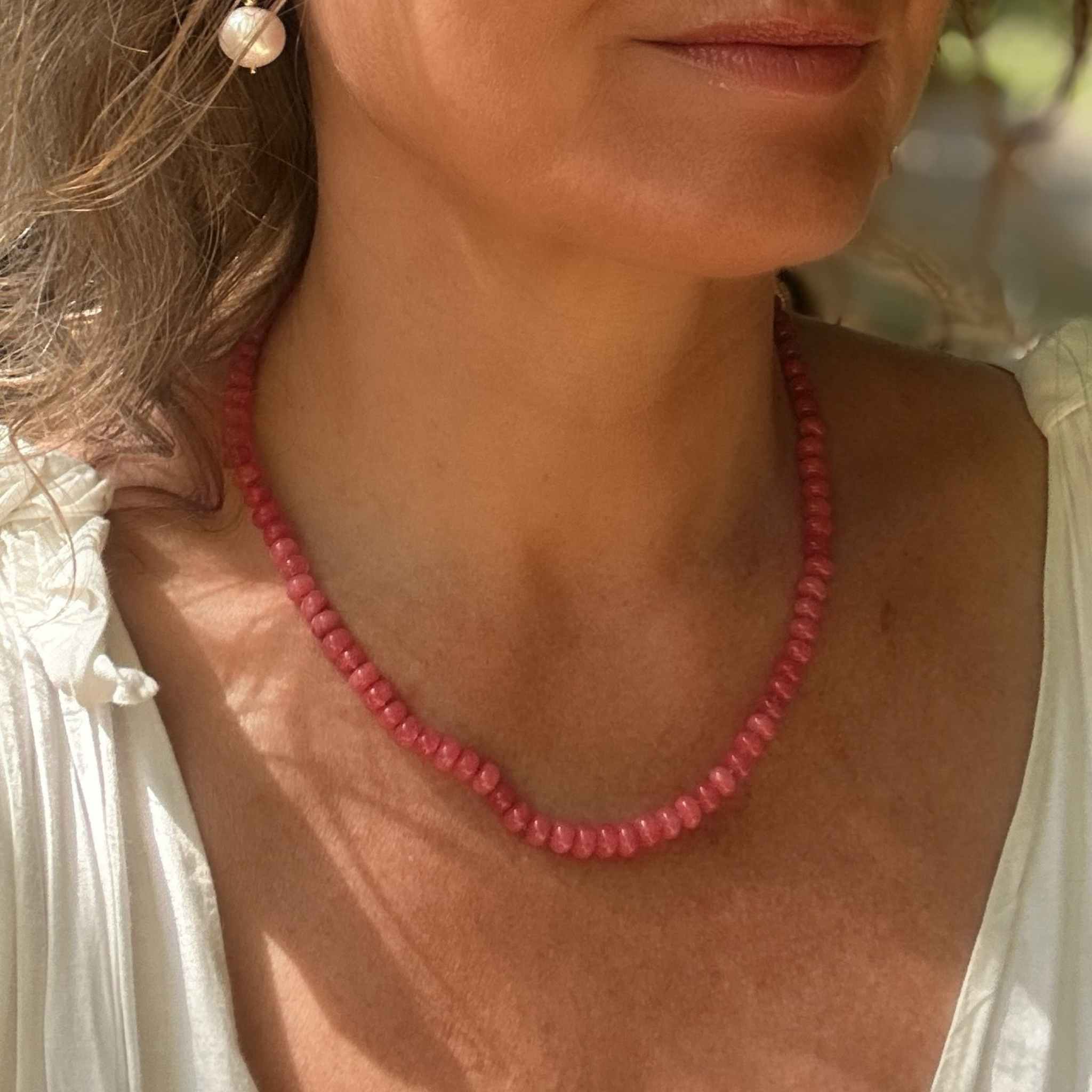Woman wearing Rósa blush pink jade necklace with gold vermeil extender chain, photographed against a white summer dress