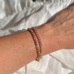 Close-up of a wrist wearing two beaded bracelets on a white fabric background