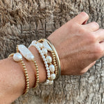 14k gold-filled baroque pearl bracelet by RAW Copenhagen, shown stacked with other freshwater pearl and hematite 
bracelets.